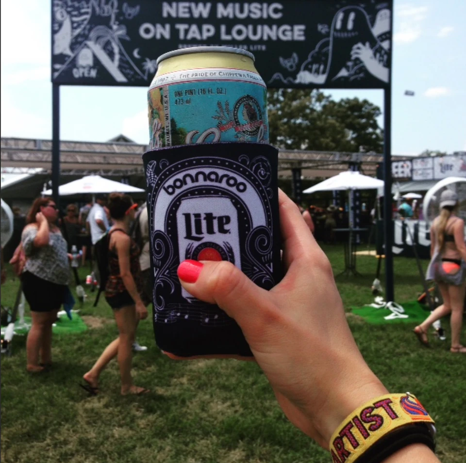 A festival attendee holds a drink inside a Miller Lite Bonnaroo sleeve.