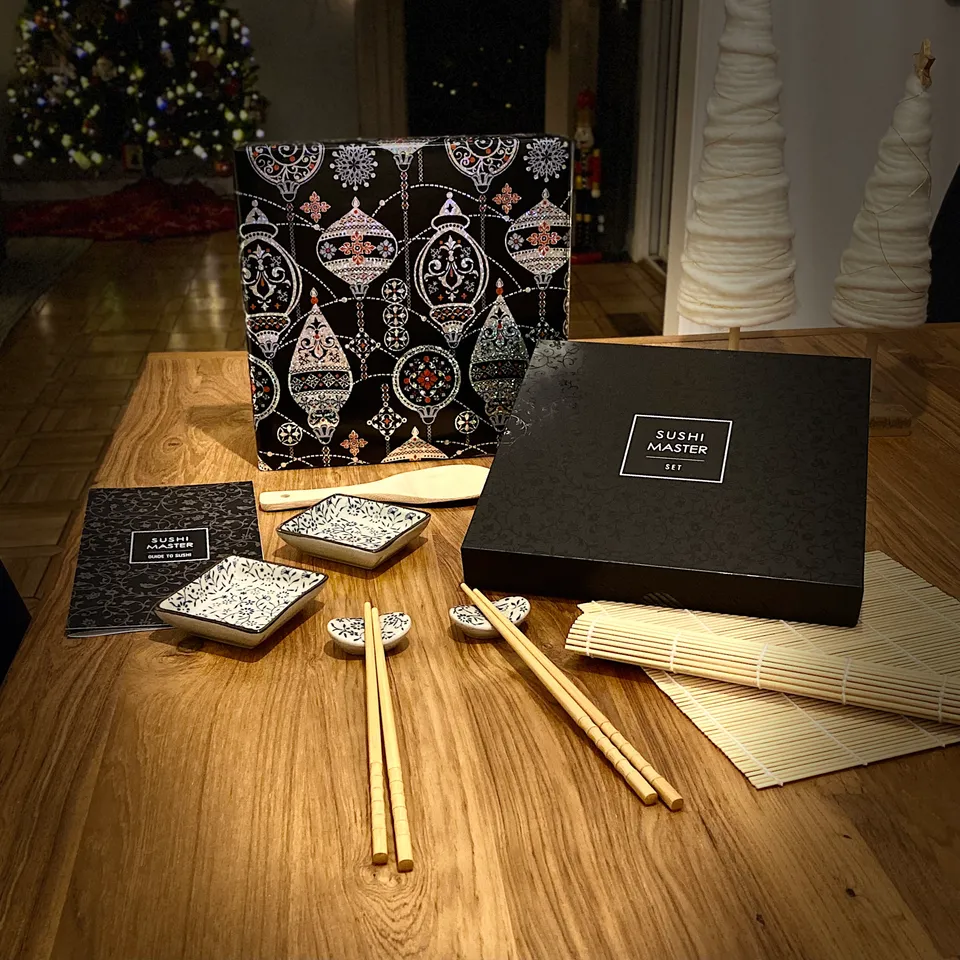The Sushi Master Set on a wooden table with a holiday-patterned gift box and candlelight