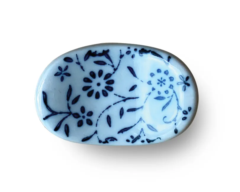 A small oval blue-and-white floral ceramic chopstick rest